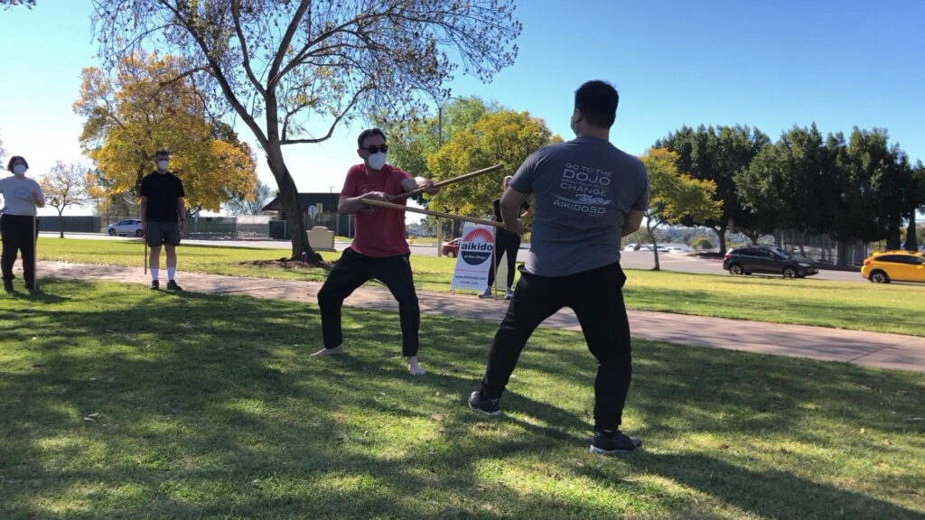 Sensei and a student demonstrating a thrust to the chest, one step of the 5th kumi jo - a partner practice with wooden staffs.