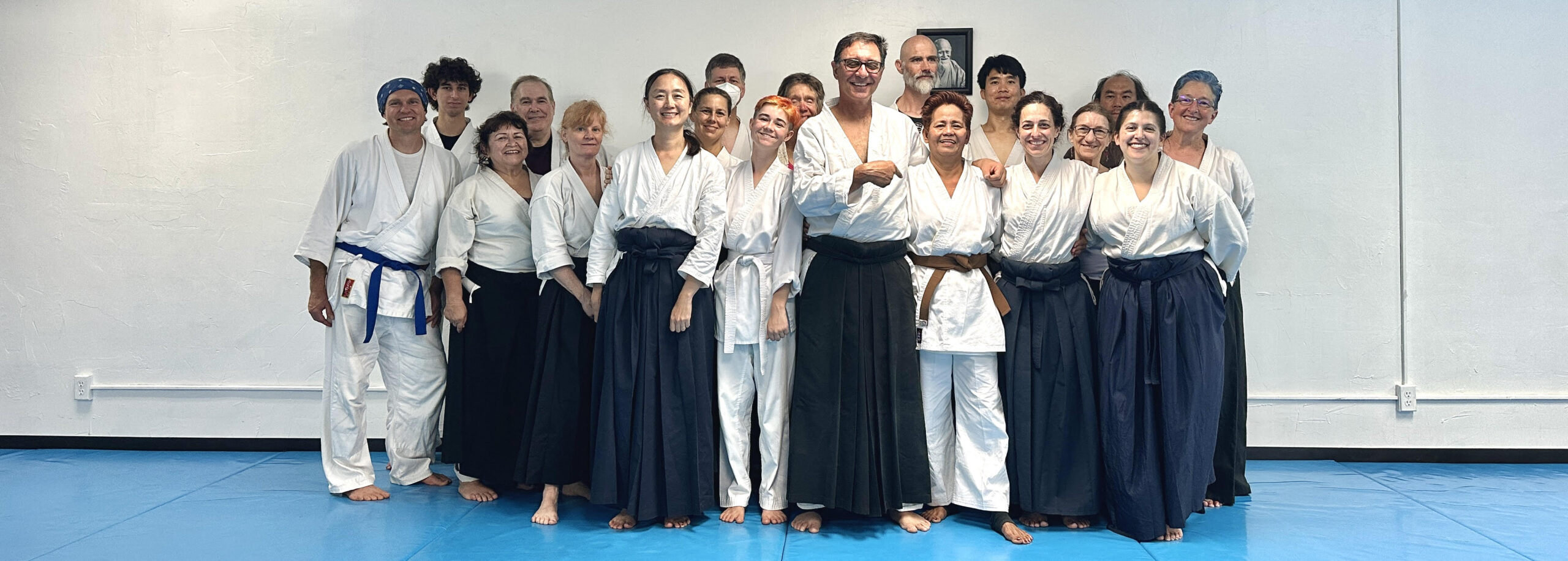 Group photo of members of Aikido of San Diego, on the mat and dressed in training uniforms, following Ana Allen's 1st-kyu exam. Photo by Christine Cessna.