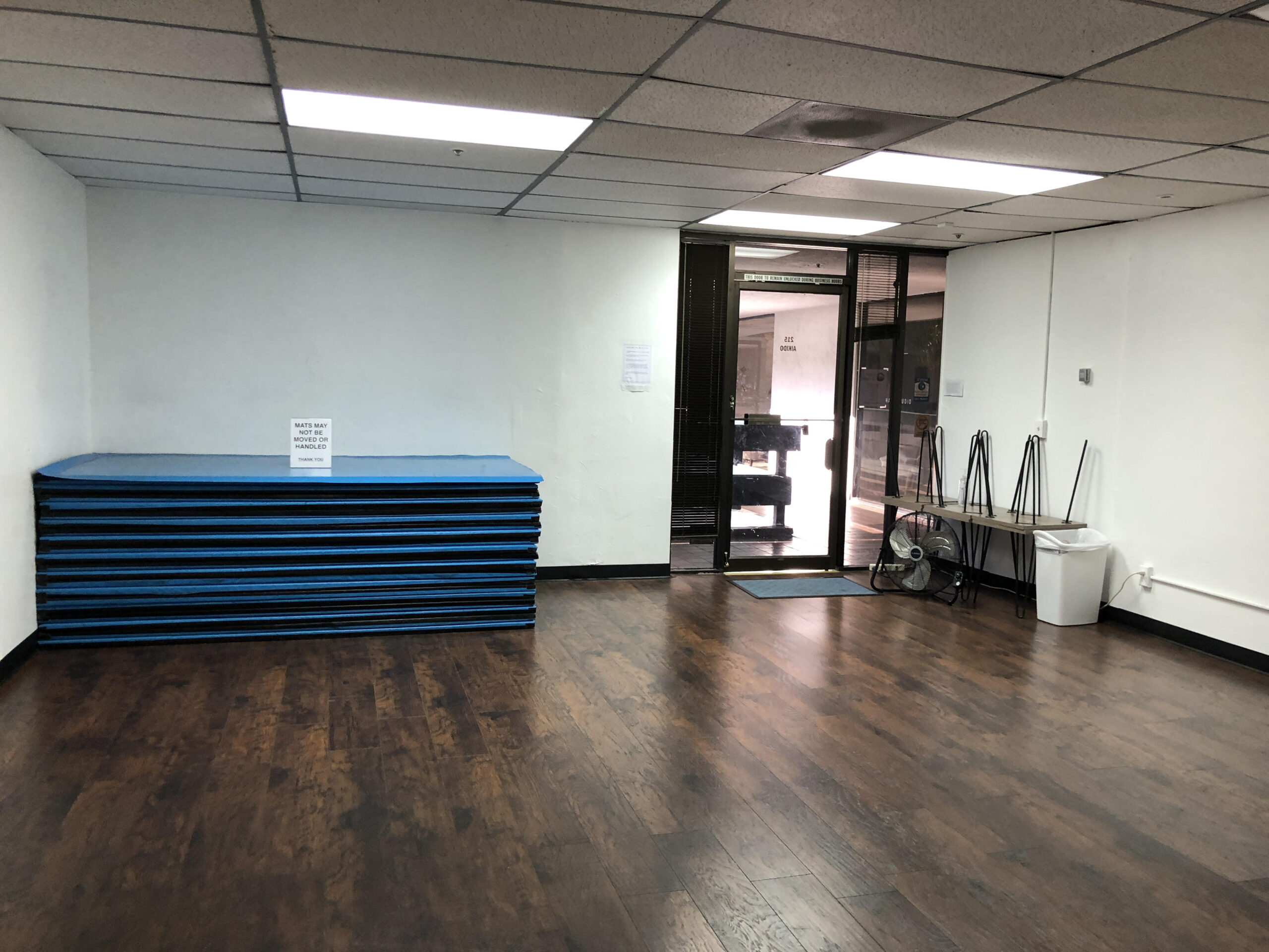 Photo of a clean, tidy dojo, with mats neatly stacked in one corner.